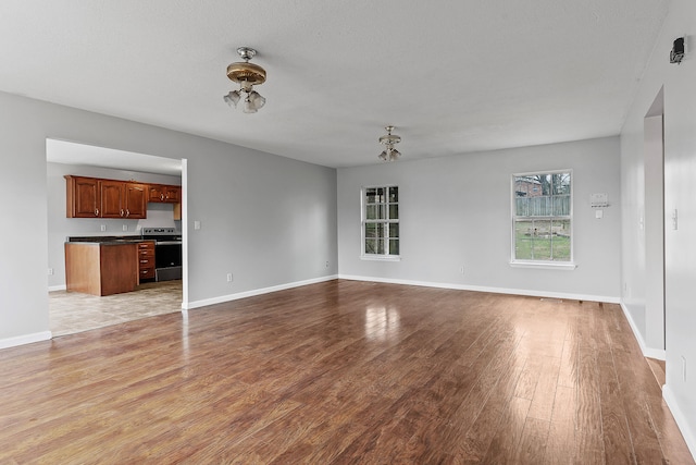 unfurnished living room with light wood-type flooring and a textured ceiling