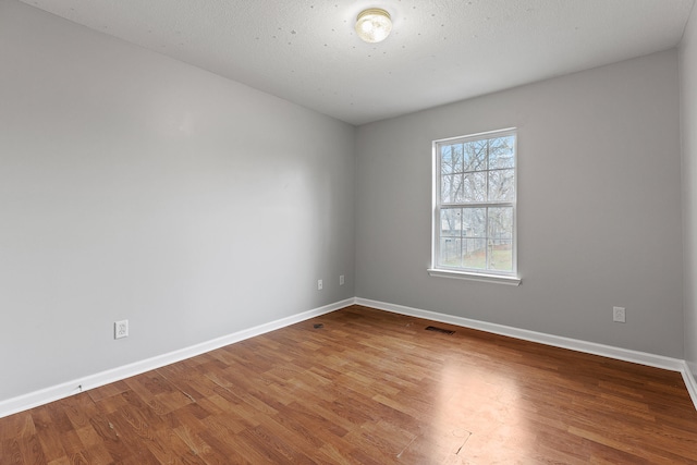 unfurnished room featuring hardwood / wood-style floors and a textured ceiling