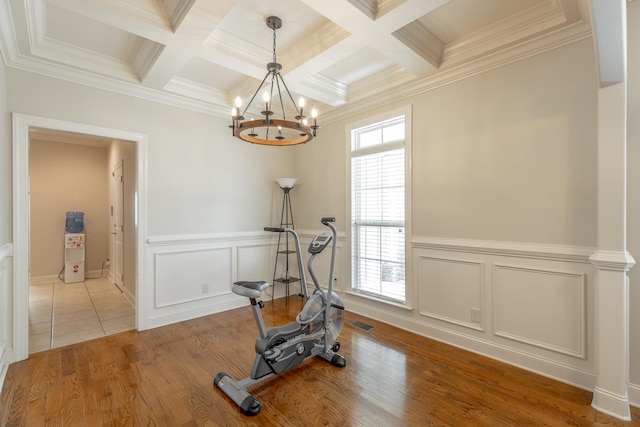 workout room featuring coffered ceiling, hardwood / wood-style floors, and an inviting chandelier