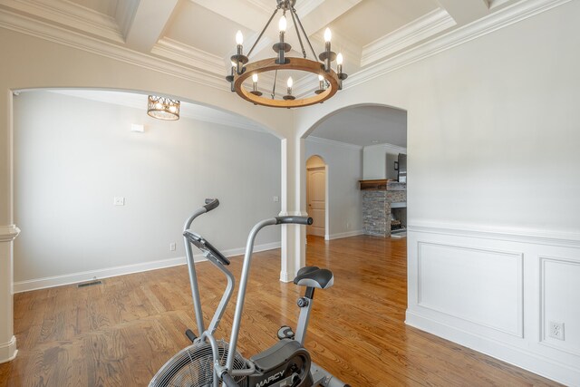 workout room featuring an inviting chandelier, wood-type flooring, and a fireplace