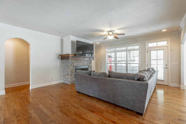 living room with ceiling fan, ornamental molding, wood-type flooring, and a fireplace