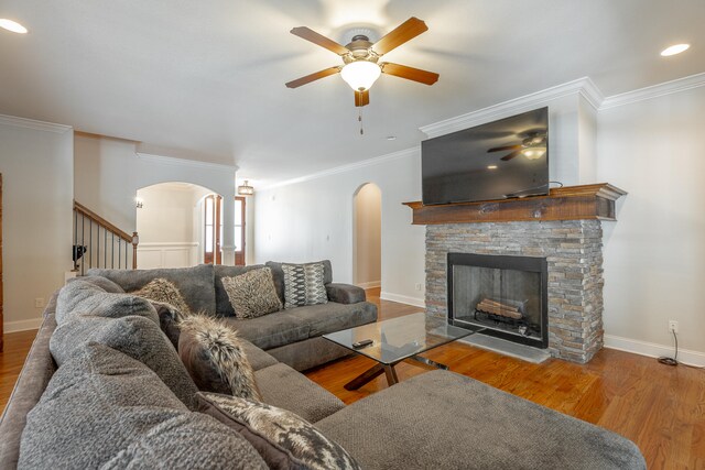 living room featuring a fireplace, crown molding, hardwood / wood-style floors, and ceiling fan