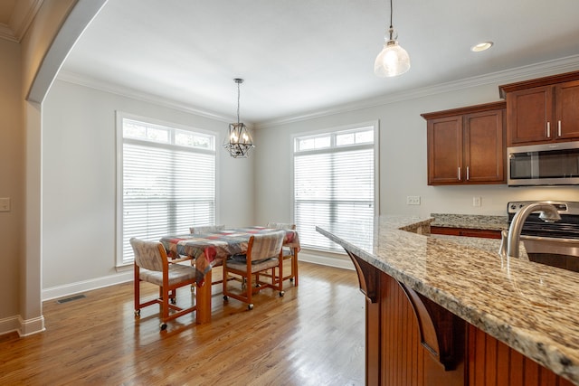 dining room featuring ornamental molding, an inviting chandelier, and light hardwood / wood-style floors