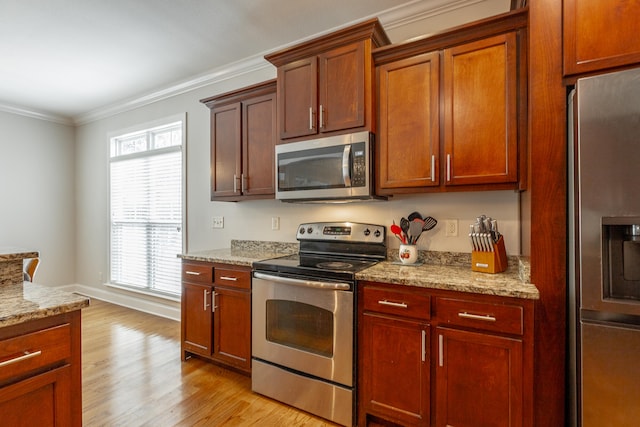 kitchen featuring crown molding, light wood-type flooring, light stone countertops, and appliances with stainless steel finishes