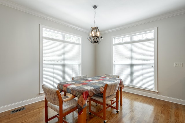 dining area featuring light wood-type flooring, an inviting chandelier, and ornamental molding