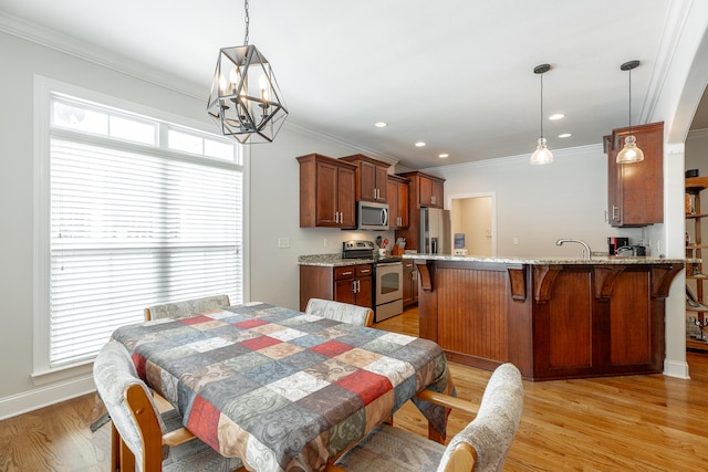 dining area featuring light wood-type flooring, a notable chandelier, and ornamental molding