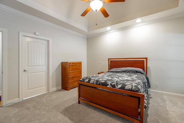 bedroom with ceiling fan, light colored carpet, a raised ceiling, and crown molding