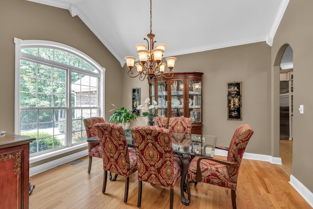 dining area featuring light wood-type flooring, ornamental molding, a chandelier, and a healthy amount of sunlight