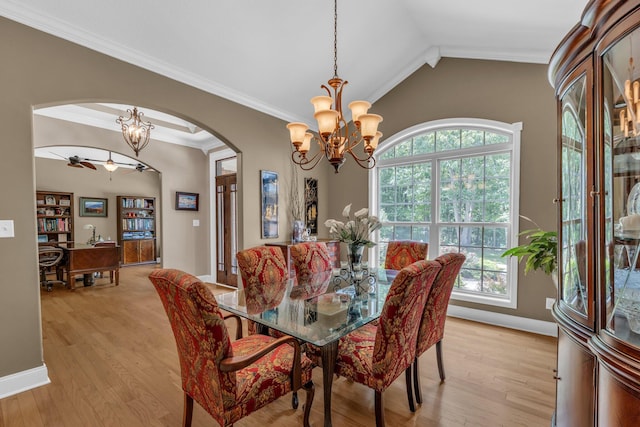 dining space featuring crown molding, plenty of natural light, vaulted ceiling, and light wood-type flooring