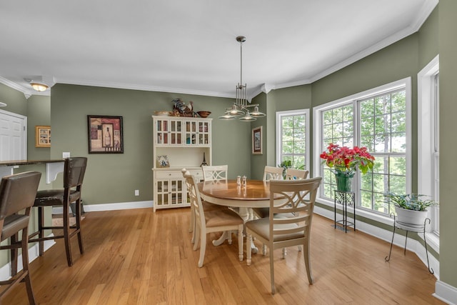 dining room featuring light wood-type flooring, crown molding, and a notable chandelier