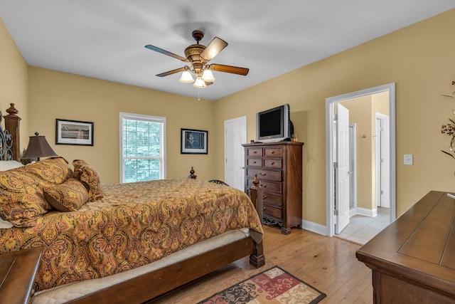 bedroom with ceiling fan, connected bathroom, and light hardwood / wood-style floors