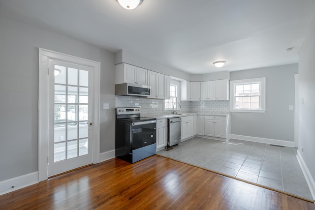 kitchen featuring appliances with stainless steel finishes, white cabinetry, light hardwood / wood-style flooring, and sink