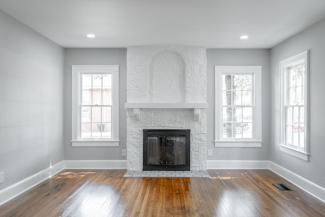 unfurnished living room featuring plenty of natural light, dark hardwood / wood-style flooring, and a fireplace