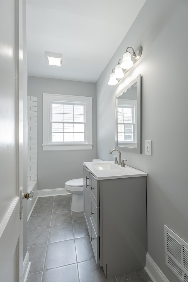 bathroom with a wealth of natural light, vanity, toilet, and tile patterned flooring