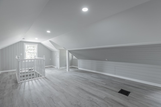 additional living space featuring vaulted ceiling, hardwood / wood-style flooring, and wood walls