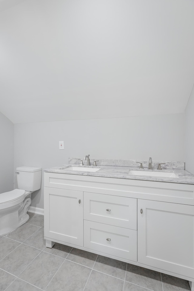 bathroom with tile patterned flooring, vanity, toilet, and vaulted ceiling