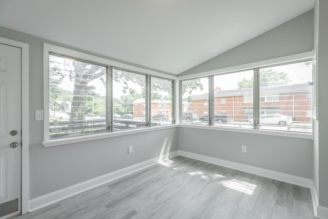 unfurnished sunroom featuring vaulted ceiling and plenty of natural light