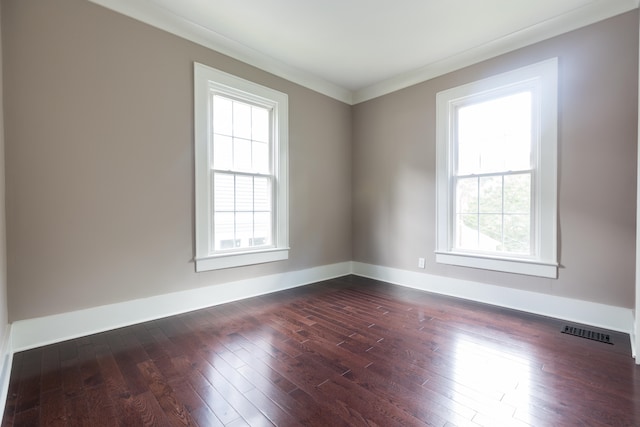 empty room featuring dark wood-type flooring, a wealth of natural light, and ornamental molding