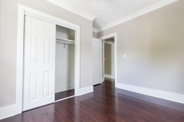 unfurnished bedroom featuring ornamental molding, a closet, and dark hardwood / wood-style floors