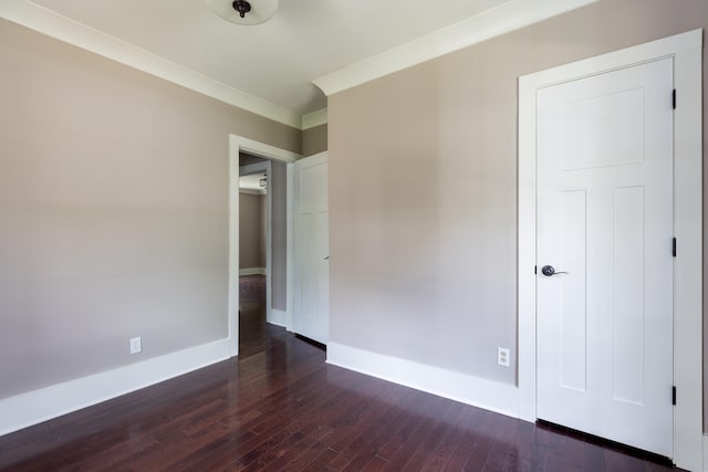 unfurnished bedroom featuring crown molding and dark wood-type flooring