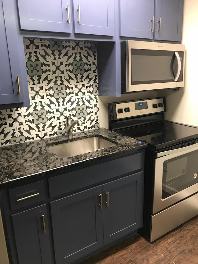 kitchen featuring dark hardwood / wood-style floors, backsplash, stainless steel appliances, sink, and dark stone countertops