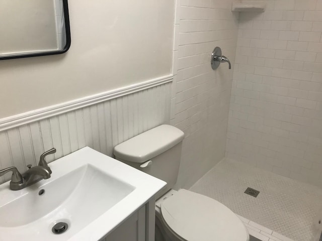 bathroom with tiled shower, toilet, and vanity