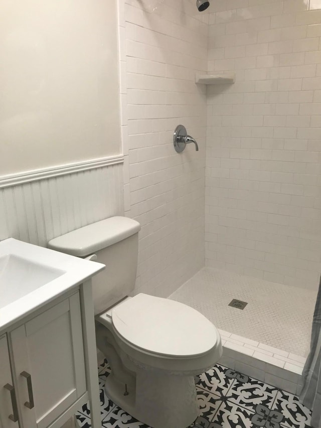 bathroom with vanity, toilet, tiled shower, and tile patterned flooring