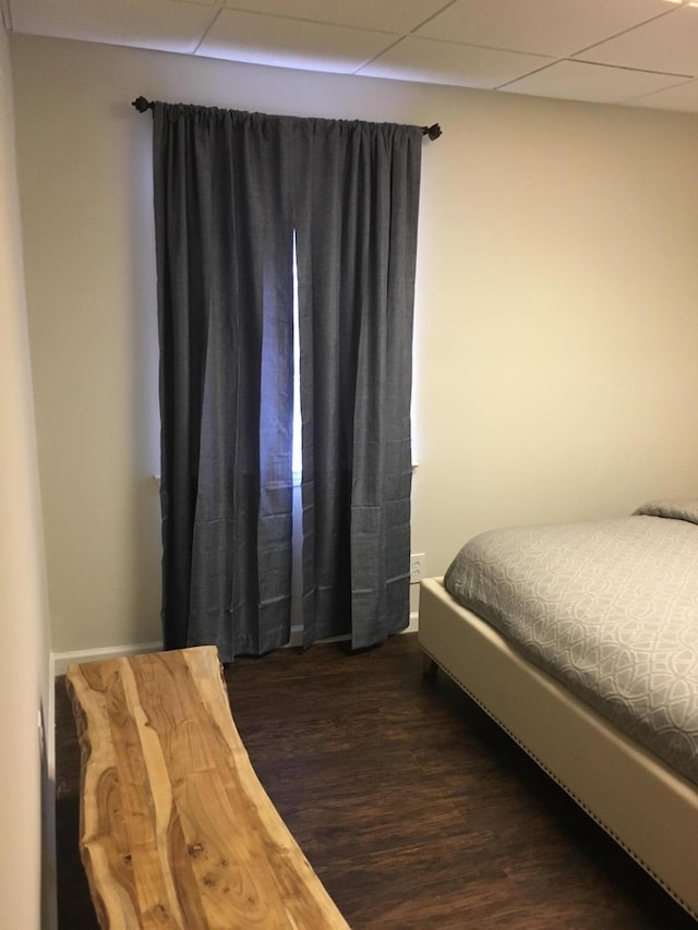 bedroom with dark hardwood / wood-style flooring and a drop ceiling