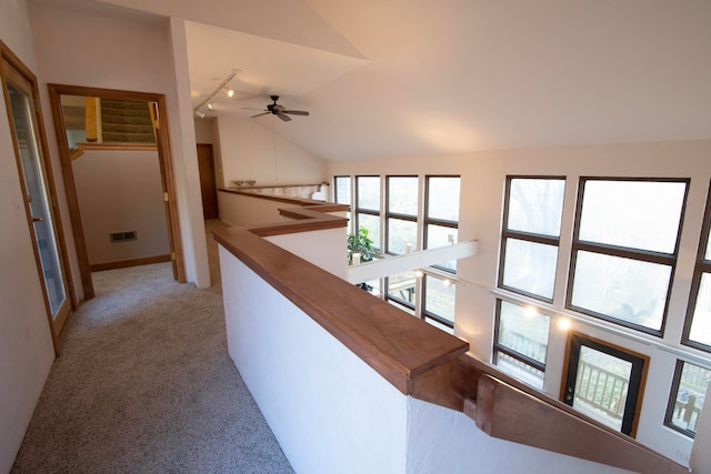 corridor with a wealth of natural light, light colored carpet, and vaulted ceiling