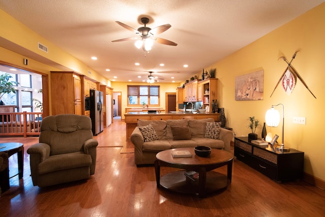 living room featuring a textured ceiling, hardwood / wood-style flooring, and ceiling fan