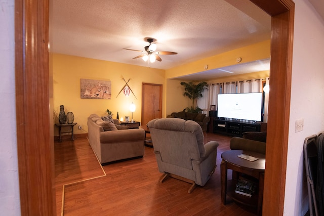 living room with hardwood / wood-style floors, a textured ceiling, and ceiling fan