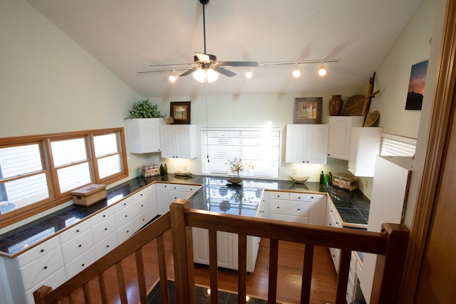 kitchen with hardwood / wood-style flooring, ceiling fan, rail lighting, white cabinets, and vaulted ceiling