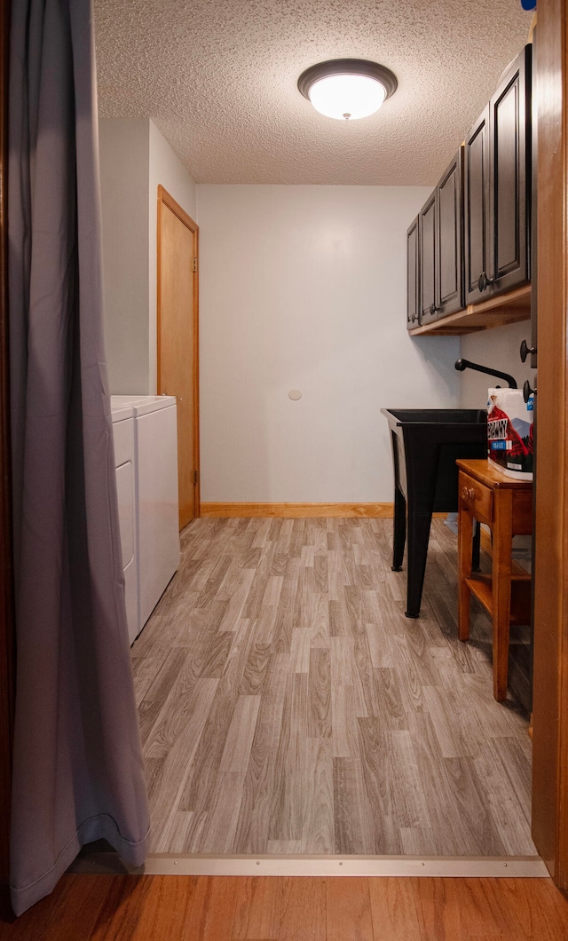 washroom with separate washer and dryer, a textured ceiling, and light hardwood / wood-style floors