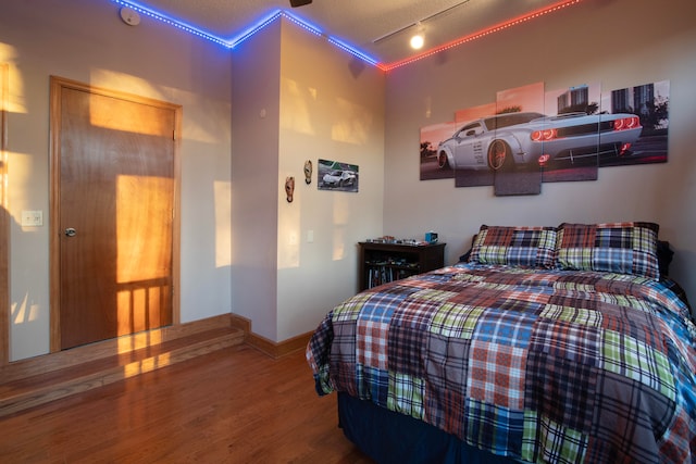 bedroom featuring a textured ceiling, track lighting, ornamental molding, and hardwood / wood-style flooring