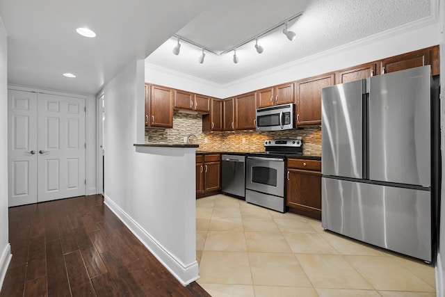 kitchen featuring crown molding, backsplash, stainless steel appliances, and light hardwood / wood-style floors