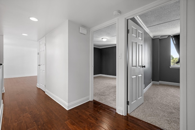 corridor featuring dark hardwood / wood-style floors, crown molding, and a textured ceiling