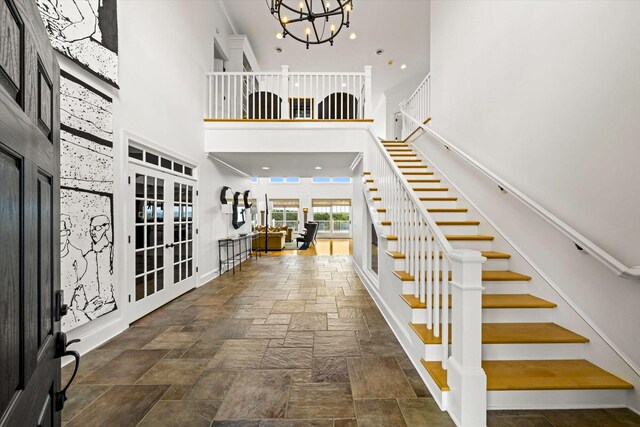 foyer featuring a high ceiling, an inviting chandelier, and french doors