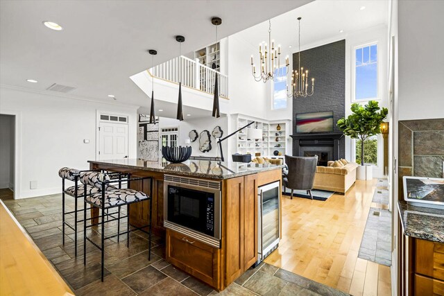 kitchen with dark stone countertops, a fireplace, beverage cooler, dark wood-type flooring, and stainless steel microwave