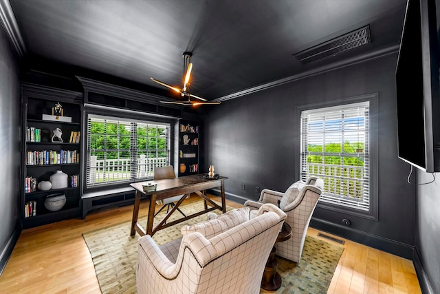 office area with ornamental molding, light hardwood / wood-style flooring, and built in shelves