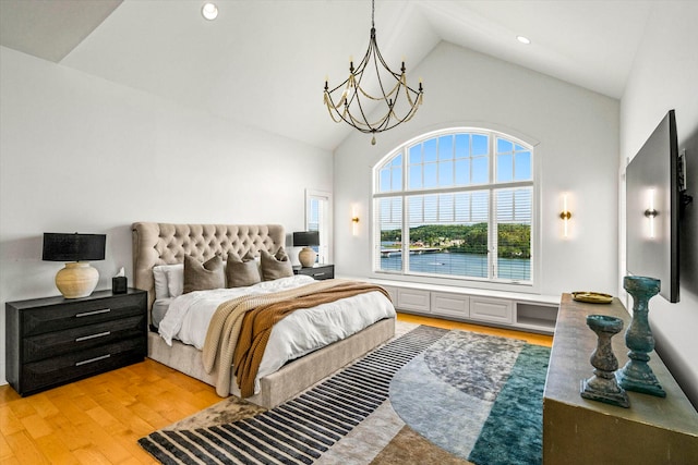 bedroom featuring high vaulted ceiling, light hardwood / wood-style flooring, and a chandelier