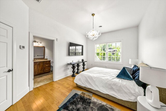 bedroom featuring light hardwood / wood-style flooring, a notable chandelier, and ensuite bathroom