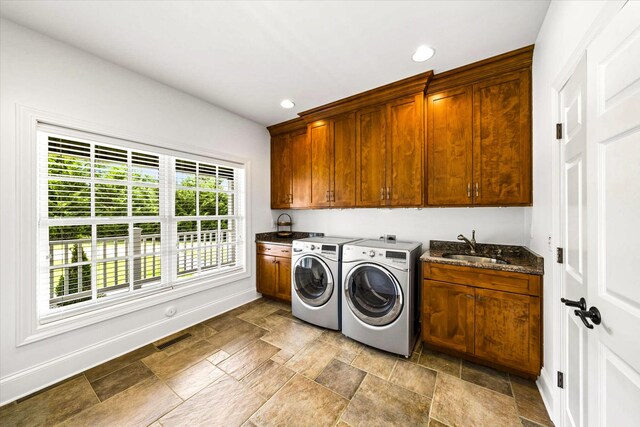 clothes washing area featuring washing machine and clothes dryer, cabinets, and sink