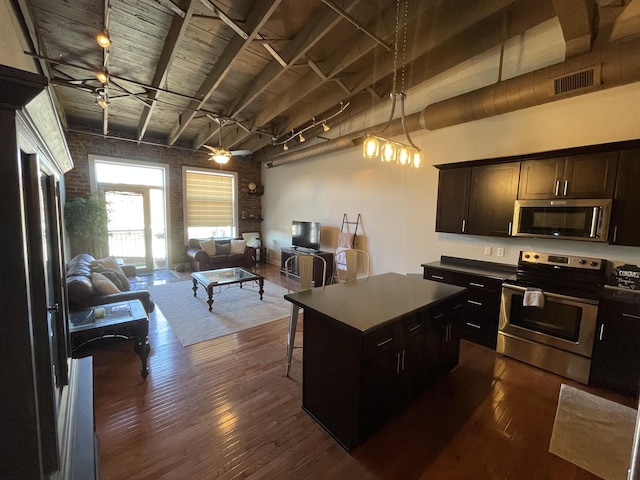 kitchen with decorative light fixtures, a center island, ceiling fan, dark wood-type flooring, and appliances with stainless steel finishes