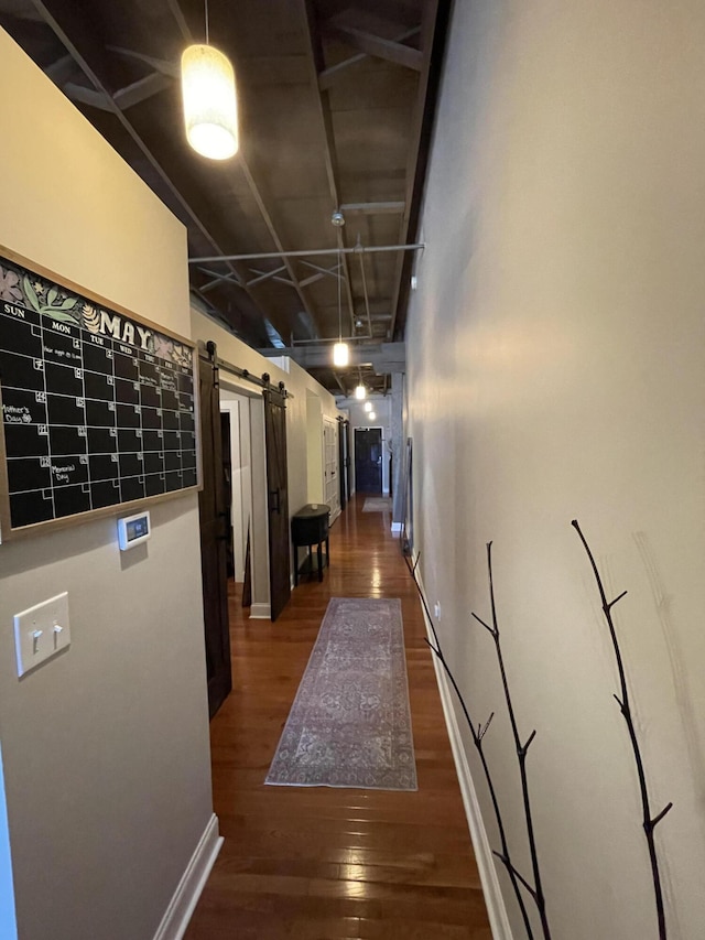 hall featuring a barn door and dark wood-type flooring