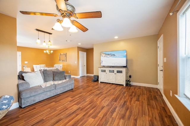 living room featuring ceiling fan with notable chandelier and hardwood / wood-style flooring