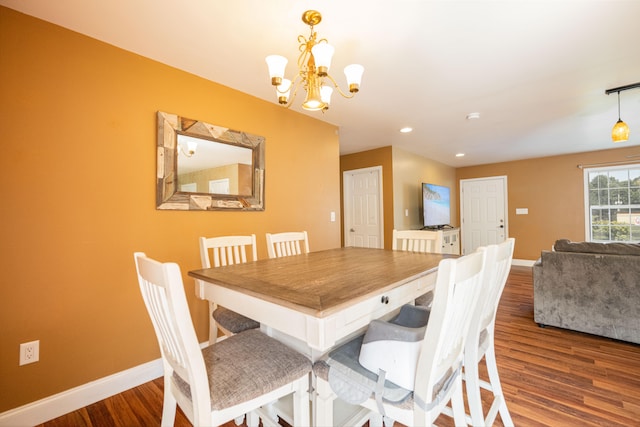 dining space with wood-type flooring and an inviting chandelier