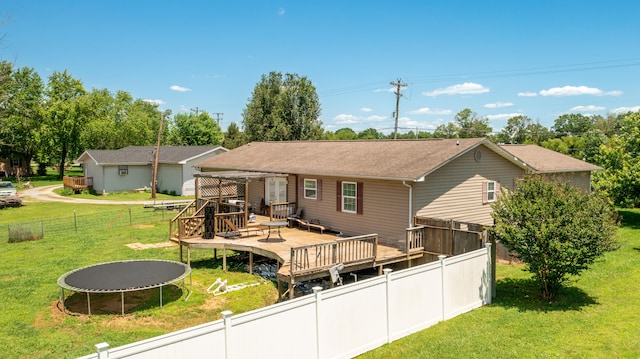 back of property featuring a trampoline, a wooden deck, and a yard