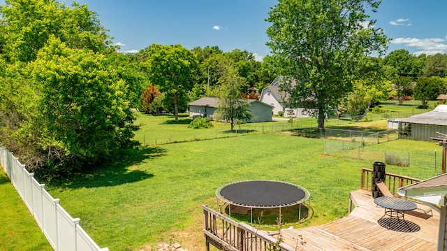 view of yard featuring a trampoline and a wooden deck