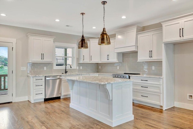 kitchen with appliances with stainless steel finishes, white cabinetry, a kitchen island, and premium range hood