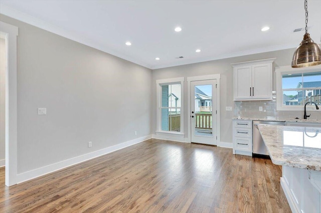 kitchen with white cabinets, dishwasher, light wood-type flooring, light stone countertops, and pendant lighting